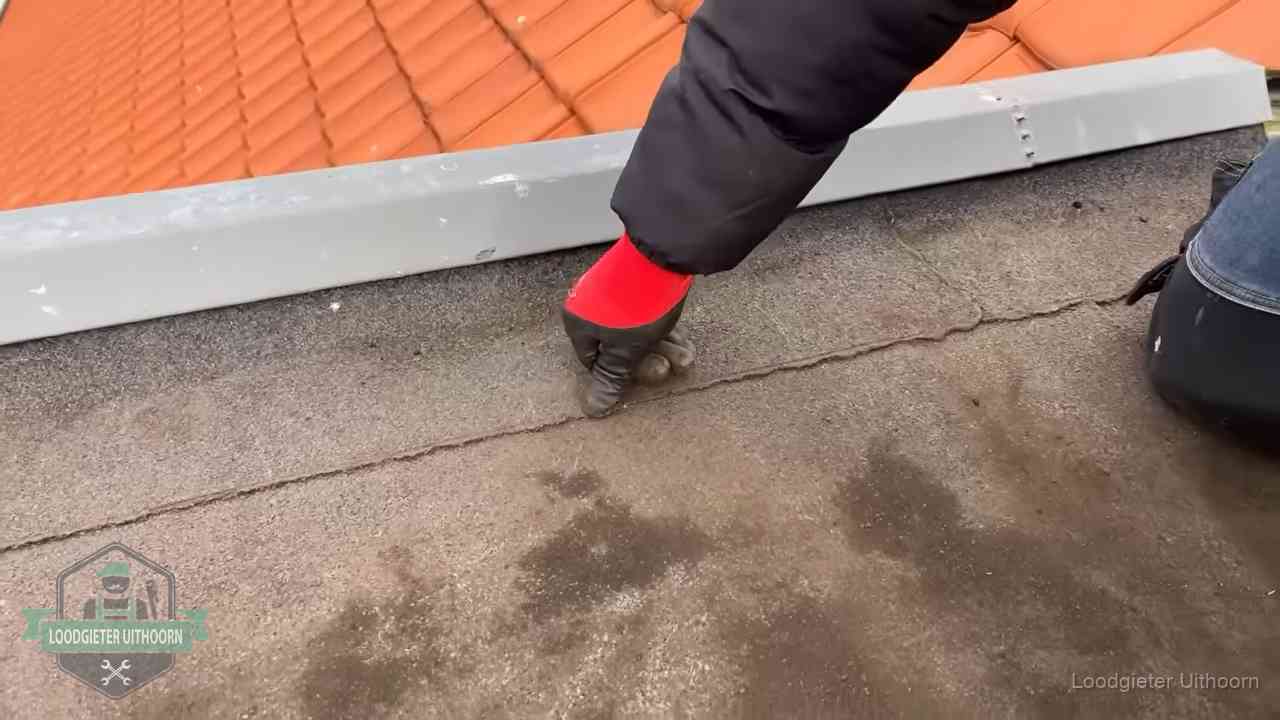 Lekkage bij de naad van een plat dak in Uithoorn Vakman wijst een naad met vochtplekken aan op een bitumen plat dak in Uithoorn
