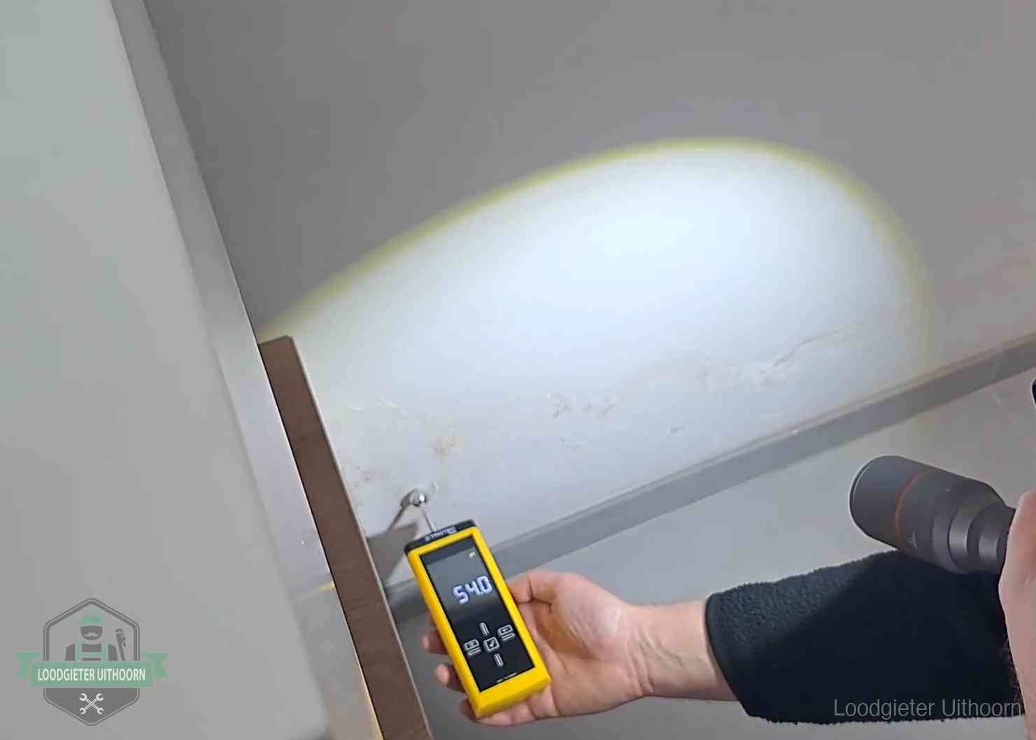 Vochtmeter tegen een natte wand met lekkagesporen in Uithoorn