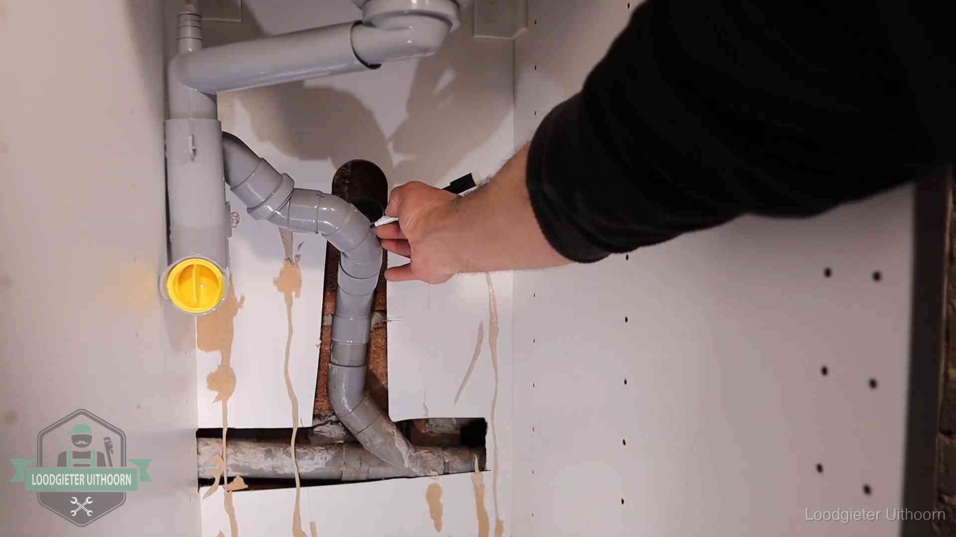 Loodgieter voor verhuurders en bedrijven in Uithoorn Loodgieter markeert een pvc-afvoerbuis onder een gootsteen in Uithoorn