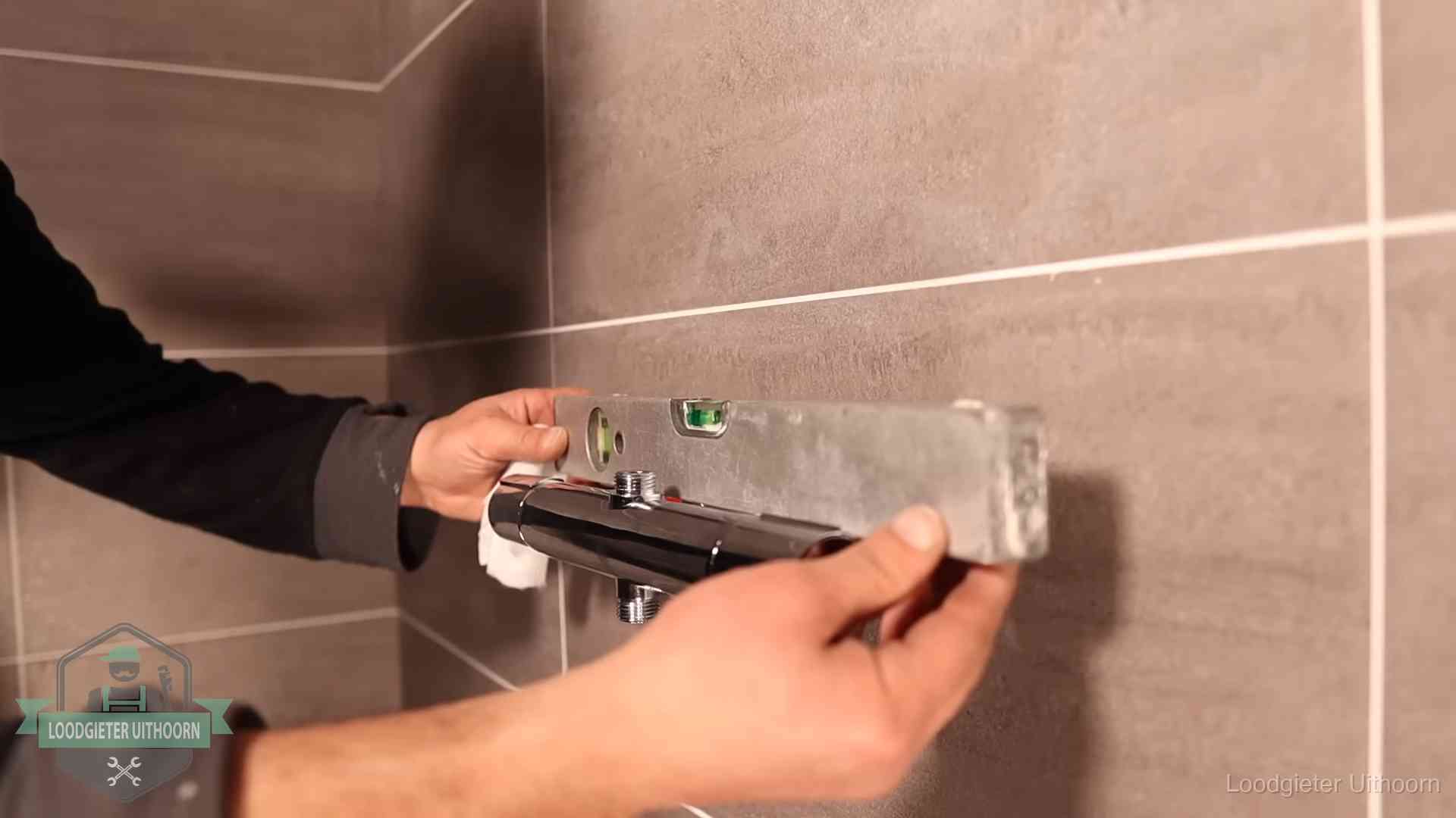 Loodgietersbedrijf voor sanitair in Uithoorn Loodgieter lijnt een douchekraan uit met een waterpas in een woning in Uithoorn