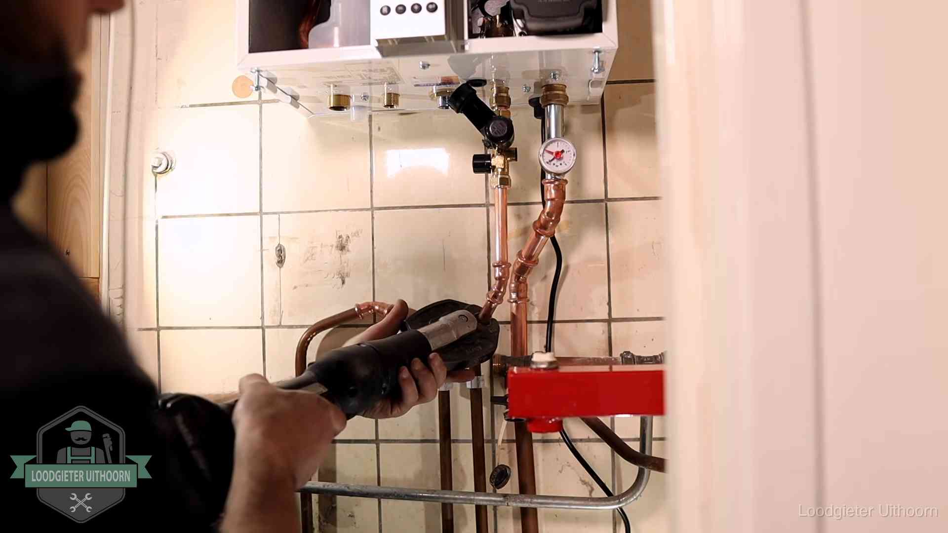 Monteur werkt aan de leidingen onder een cv-ketel in Uithoorn