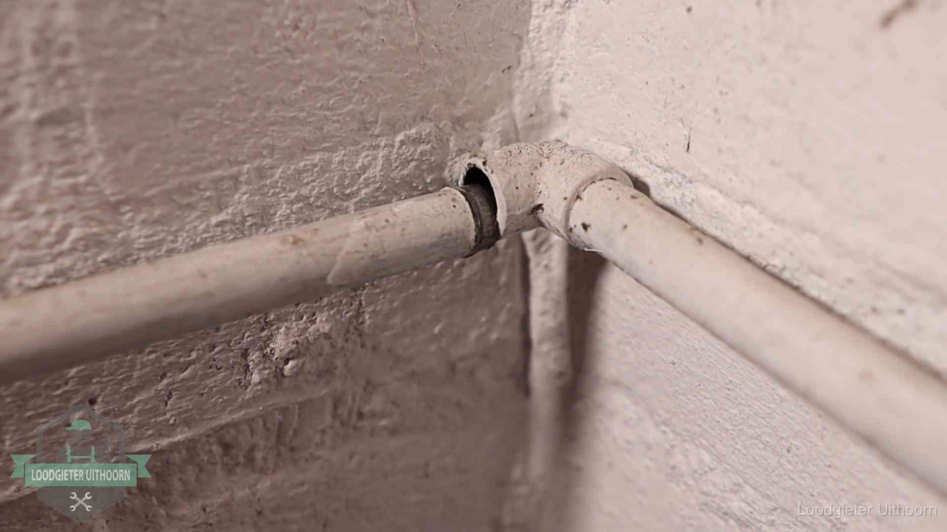 Oude geverfde waterleiding met een losliggende fitting in een woning in Uithoorn