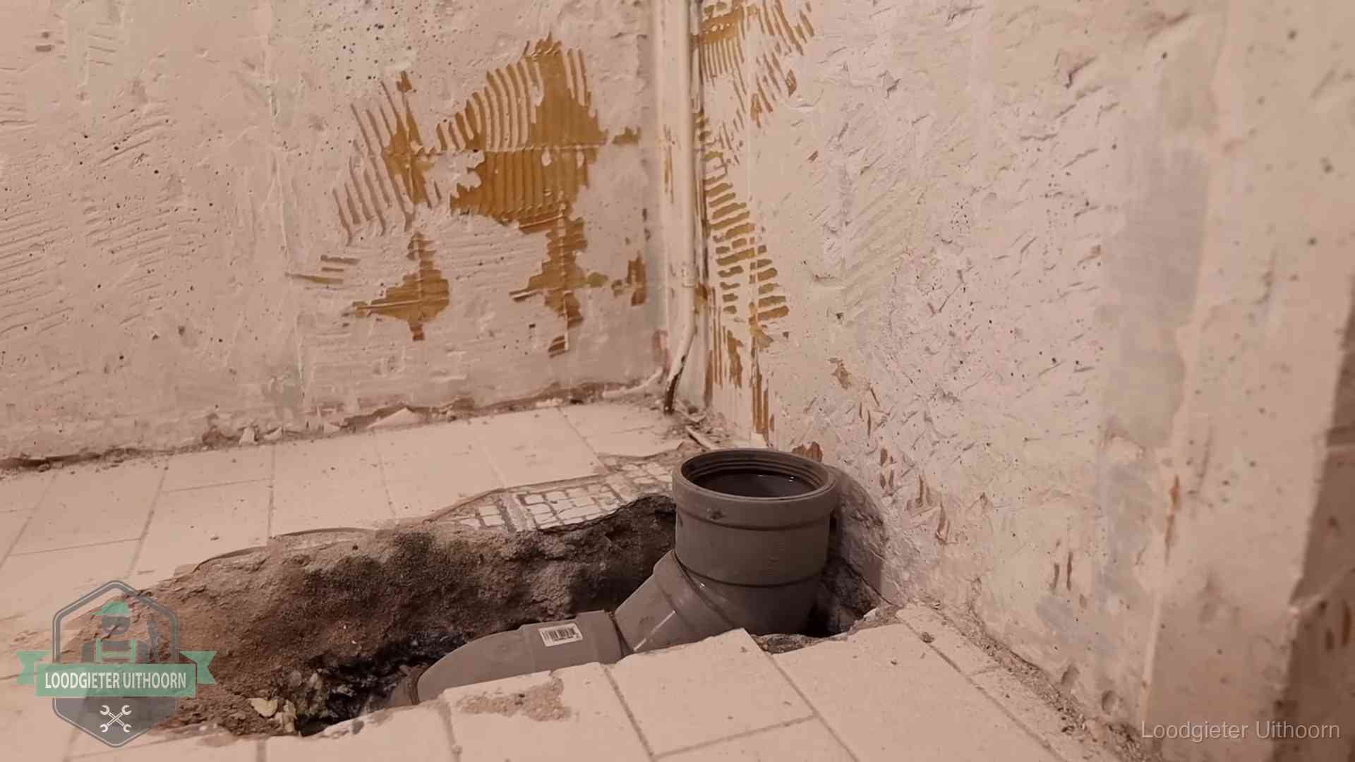 Verzakt riool herstellen in Uithoorn Opengebroken vloer met een nieuwe pvc-rioolbocht in een gegraven sleuf in Uithoorn