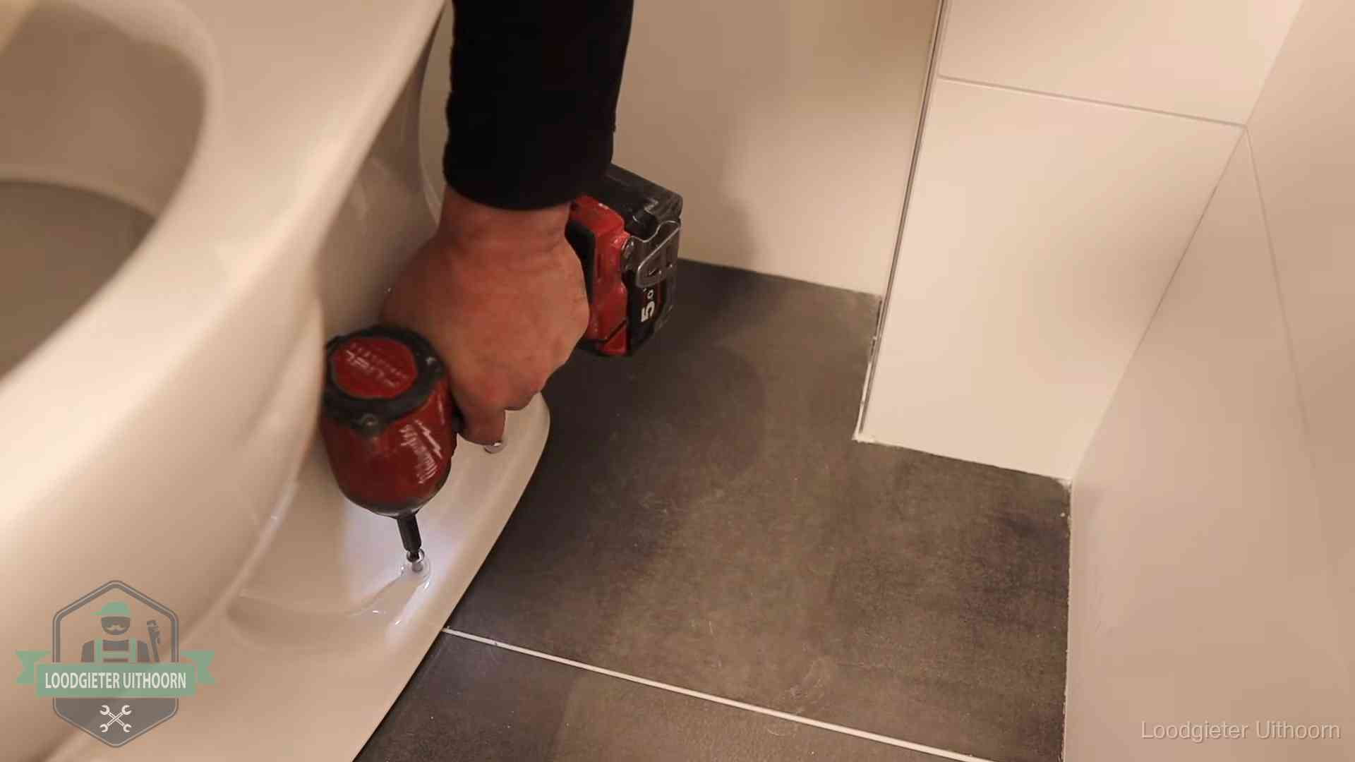 Kosten wc ontstoppen in Uithoorn Loodgieter zet de voet van een wc-pot vast op de tegelvloer in Uithoorn